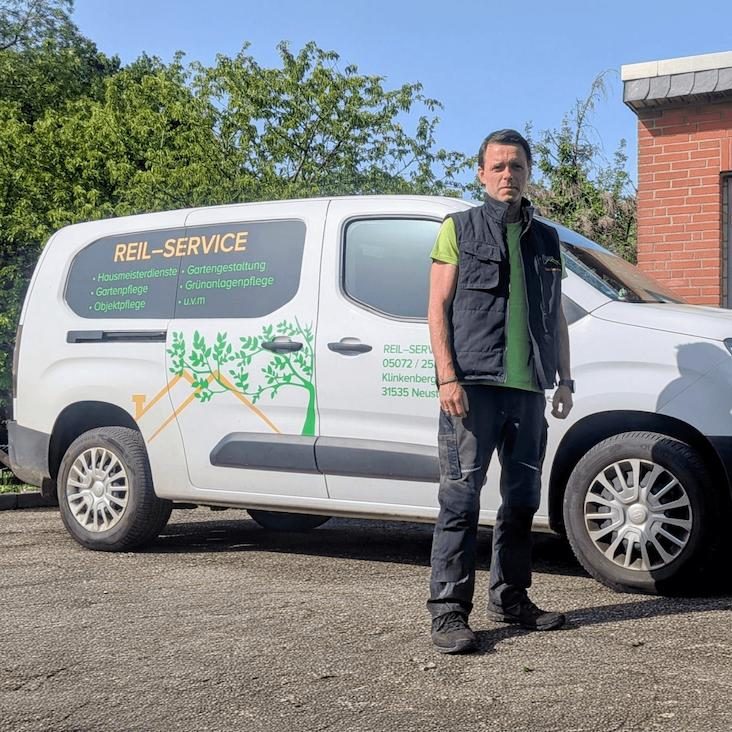 Reil-Service Neustadt am Rübenberge. JPG Mann in Arbeitskleidung steht neben einem weißen Servicefahrzeug.